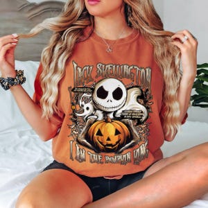 Puede incluir: Camiseta naranja con Jack Skellington de The Nightmare Before Christmas. El dise&ntilde;o incluye la cara de Jack, una calabaza y el texto "I Am The Pumpkin King". Texto adicional: "Christmas Time is Buzzing in My Skull."