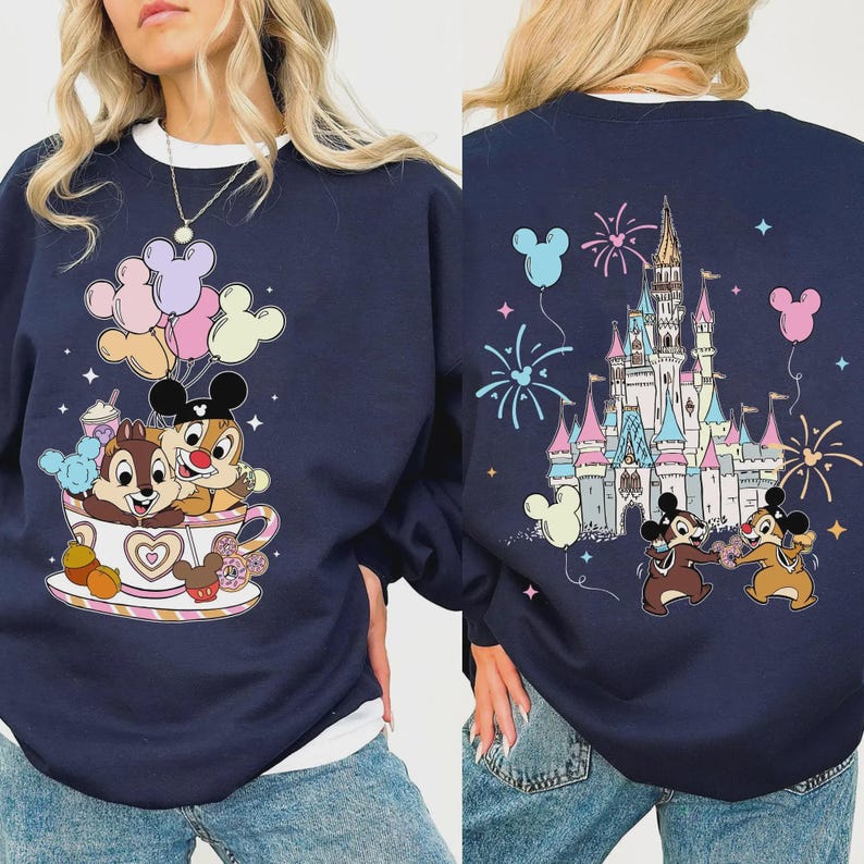 May include: Navy blue sweatshirt featuring Chip and Dale in a teacup with Mickey Mouse balloons. The back of the sweatshirt displays a castle, fireworks, and Chip and Dale. The sweatshirt has a white collar.