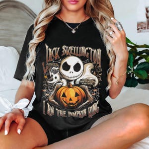 Puede incluir: Camiseta negra con Jack Skellington de The Nightmare Before Christmas. El dise&ntilde;o incluye a Jack sosteniendo una calabaza, con texto que dice "Jack Skellington" y "I am the Pumpkin King."