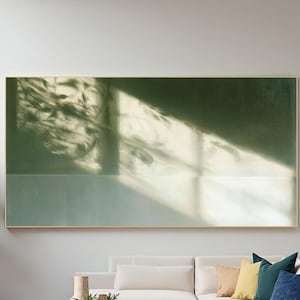 May include: A large rectangular wall art piece featuring a deep forest green upper section and a lighter sage green lower section. A bright diagonal beam of light cuts across the canvas, casting intricate, dark leaf-shaped shadows throughout.