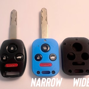 May include: Three car key fobs, one black, one blue, and one black key fob cover. The black and blue fobs have silver keys and red "PANIC" buttons. The text "NARROW" and "WIDE" are at the bottom.