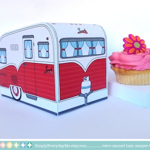 May include: A red and white camper-trailer shaped box with a pink cupcake with a pink and orange flower on top. The box has the words "Simply Everyday Me" on the side. The cupcake is sitting on a blue and white base.