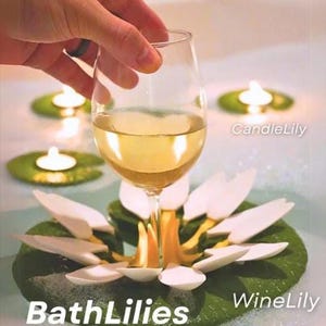 May include: A wine glass with a pale liquid sits above a lily pad with white petals. The image includes the words "BathLilies", "WineLily", and "CandleLily". Several floating candles are also visible in the water.
