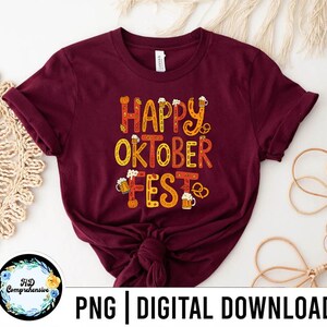 May include: A maroon t-shirt with the words "HAPPY OKTOBER FEST" in orange and yellow lettering. The design includes beer steins, pretzels, and pumpkins. The bottom of the shirt has the text "PNG | DIGITAL DOWNLOAD".