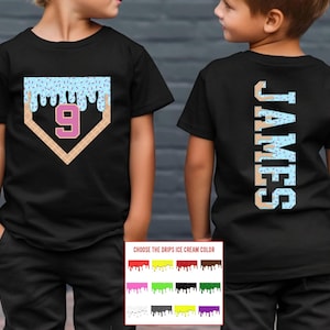 May include: Black t-shirt featuring a baseball home plate design with a number 9 in pink. The top of the home plate has blue ice cream drips with sprinkles. The back of the shirt has the name "JAMES" in a vertical design.