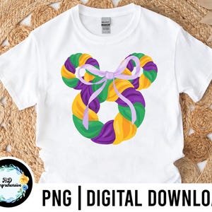Könnte beinhalten: Weißes T-Shirt mit einem Mardi Gras-Design. Das Design zeigt eine lila Schleife und eine kreisförmige Anordnung aus grünen, gelben und lila Elementen. Der Text unten lautet "PNG | DIGITALER DOWNLOAD".