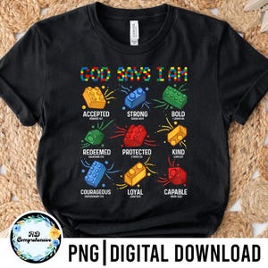 May include: Black t-shirt with the text "GOD SAYS I AM" in colorful block letters. Below, various block designs with words like "Accepted," "Strong," and "Bold" are displayed. The shirt also includes Bible verses.