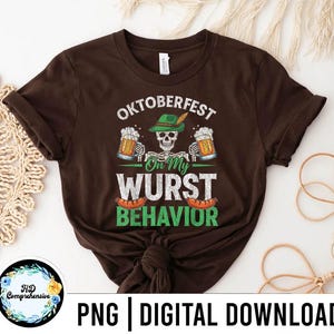 May include: A brown t-shirt with the text "Oktoberfest On My Wurst Behavior" in white and green. The design includes a skull wearing a green hat, beer mugs, and sausages. The shirt is a digital download.