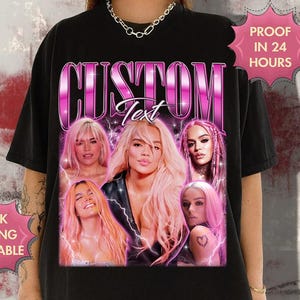 May include: Black t-shirt featuring a custom design with the word "CUSTOM" in a pink, retro font. The design includes multiple images of a woman with pink hair. Text on the shirt says "Text".