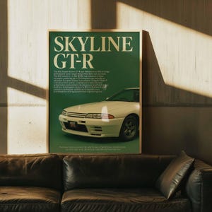 May include: A framed poster featuring a white Nissan Skyline GT-R car on a green background. The poster has the text "SKYLINE GT-R" in large white letters at the top. The car is positioned on the right side of the poster.