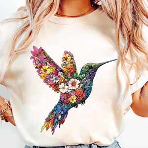 a woman wearing a t - shirt with a hummingbird design on it
