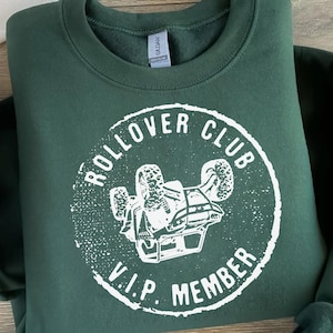 May include: Green sweatshirt with a white graphic of a rollover vehicle and the text "Rollover Club V.I.P. Member".