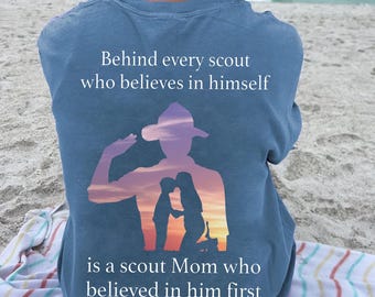 May include: A light blue t-shirt with a silhouette of a scout saluting. The text on the shirt reads "Behind every scout who believes in himself is a scout Mom who believed in him first."