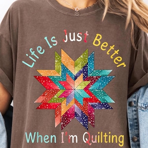 May include: A brown t-shirt with a colorful quilt block design and the text "Life is Just Better When I'm Quilting".