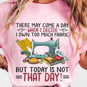 Peut inclure: T-shirt rose avec une machine à coudre, des aiguilles, du fil et du tissu. Le texte dit "Il peut arriver un jour où je déciderai que j'ai trop de tissu, mais aujourd'hui n'est pas ce jour !"
