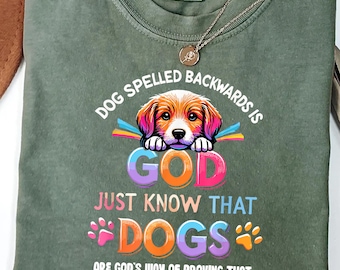 May include: Green t-shirt with a colorful graphic design featuring a dog and the text "Dog spelled backwards is God. Just know that dogs are God's way of proving that he didn't want us to walk alone."