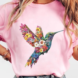 a woman wearing a pink shirt with a hummingbird on it