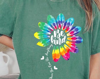 May include: Green t-shirt featuring a tie-dye flower design with the text "Be kind" in the centre. The text "In a world where you can be anything" is written around the flower.