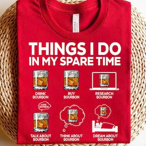 Puede incluir: Camiseta roja con el texto "Things I do in my spare time" y una lista de actividades relacionadas con el bourbon, incluyendo beber, comprar, investigar, hablar, pensar y soñar con bourbon.