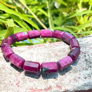 May include: A bracelet made of pink and green gemstone beads. The beads are faceted and have a rectangular shape.