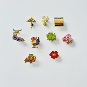 Puede incluir: Un conjunto de diez pines de esmalte que representan varios s&iacute;mbolos culturales filipinos, incluyendo un gallo, un jeepney, una flor, una palmera, una cometa, un pavo real y una flor. Los pines son todos de color dorado con detalles de esmalte de colores.