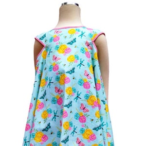 May include: A light blue sleeveless dress with a floral print featuring butterflies, dragonflies, and flowers. The dress has a pink trim around the neckline and hem.