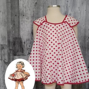 May include: Vintage inspired sewing pattern for a child's overall, tunic, or apron. The pattern is for sizes 1-4. The image shows a white fabric with red polka dots and red trim. The pattern is shown on a mannequin and a drawing of a child wearing the garment.