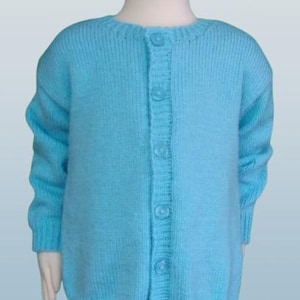 Pode incluir: Um cardigan azul claro com botões. Este suéter de malha apresenta um decote redondo e mangas compridas. Os botões são da mesma cor que o suéter. A peça de roupa é exibida num manequim, realçando o seu design.