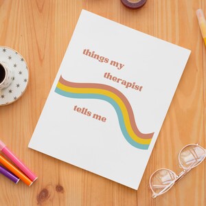 May include: A white card with a rainbow design and the text "things my therapist tells me" in brown and orange lettering.