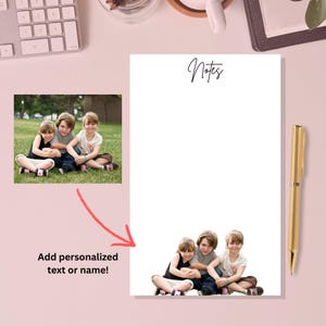 May include: A white notepad with the word "Notes" in cursive script at the top. The notepad has a photo of three children at the bottom. A gold pen rests on a pink surface. The image also includes a photo of the children and the text "Add personalized text or name!"