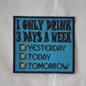 Op de afbeelding: Blauw en zwart geborduurd patch met de tekst "Ik drink maar 3 dagen per week" en een checklist met de opties "Gisteren", "Vandaag" en "Morgen", die allemaal zijn aangevinkt.