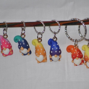 Puede incluir: Conjunto de ocho marcadores de punto de gnomo coloridos con lunares blancos y un coraz&oacute;n blanco. Los gnomos est&aacute;n unidos a anillos plateados.