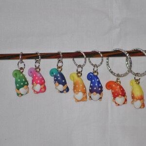 Puede incluir: Siete marcadores de punto de gnomo coloridos con lunares blancos y un coraz&oacute;n blanco en cada gnomo. Los marcadores de punto de gnomo est&aacute;n colgados en una varilla de madera.