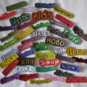 May include: A collection of colorful embroidered iron-on patches with various font styles and names, including "Dexter", "Addison", "Mystic", "Kids", "School Book", "Croissant Platinum", "Speedy", "Futura", "Seagull", "Chancery", "Felt Tip", "Matura", "Magneto", "Old English", "Showcard", "Woodstock", "Bauhaus", "Forte", "Vivaldi", "Stencil", "Small Block", "Hobo", "Chiller", "Curl", "Hana", "Revie", "Algerian", "Snap", "Fokerman", "Block 2", "Blackadder", "Athetica".