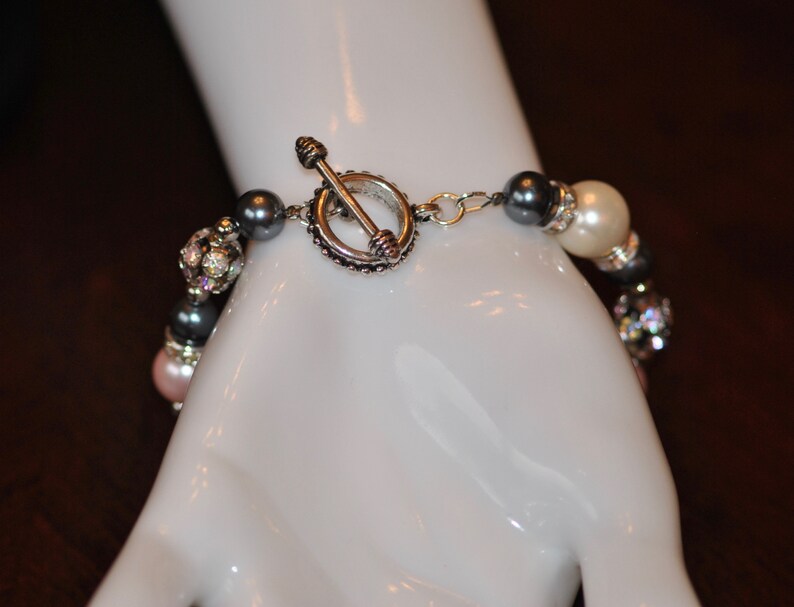 May include: A multi-strand bracelet with gray, white, and pink beads, and a silver toggle clasp.