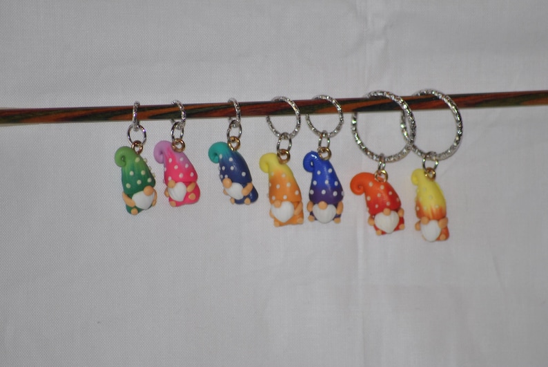 Puede incluir: Un conjunto de ocho marcadores de punto de gnome coloridos con lunares blancos. Cada marcador est&aacute; unido a un anillo plateado y tiene un coraz&oacute;n blanco en la parte delantera.