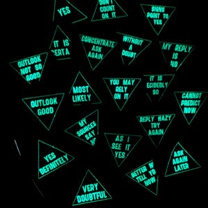 Könnte beinhalten: Eine Ansammlung leuchtend grüner Dreiecke vor schwarzem Hintergrund. Jedes Dreieck enthält einen Wahrsagespruch in weißem Text, wie z. B. „JA“, „AUSBLICK GUT“ und „FRAGEN SIE SPÄTER NOCH EINMAL“.