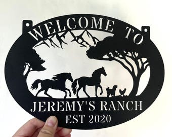 May include: Black metal oval sign with the text "Welcome to Jeremy's Ranch Est 2020". The sign features a silhouette of a mountain range, two horses, and two chickens.