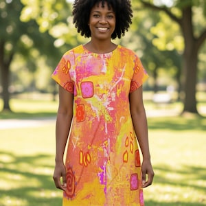 May include: A short-sleeved dress with a vibrant abstract design in shades of yellow, orange, pink, and purple. The dress features a crew neck and a knee-length hemline. The design includes geometric shapes and organic forms.