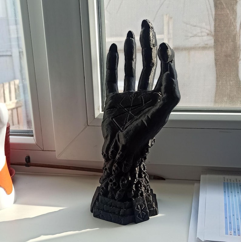 Puede incluir: Una escultura de mano negra impresa en 3D con un dise&ntilde;o detallado en la palma. La mano est&aacute; levantada con los dedos extendidos y parece estar alcanzando hacia arriba.