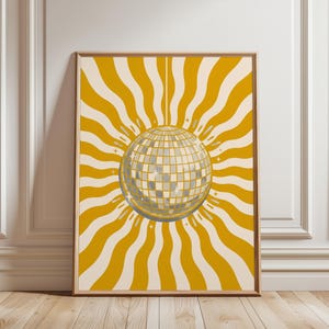 May include: A rectangular wall art print featuring a central silver disco ball with a grid pattern. The background consists of alternating wavy mustard yellow and cream-coloured vertical stripes radiating outward from the centre of the disco ball.