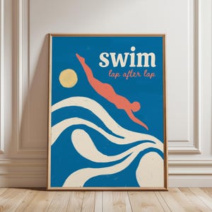 Könnte beinhalten: Ein gerahmter Kunstdruck mit blauem Hintergrund, einer korallenfarbenen Figur, die in cremefarbene Wellen eintaucht, und einem gelben Kreis als Sonne. Der Text lautet "swim" in großen weißen Buchstaben und "lap after lap" in Koralle.