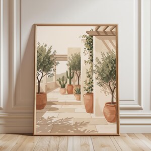 May include: A framed wall art print depicting a sunlit Mediterranean terrace with terracotta pots containing olive trees and cacti. The scene features stone flooring, light-colored walls, wooden pergola beams, and soft shadows cast by foliage.
