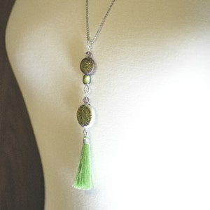 May include: A silver chain necklace with a green tassel and three round green and brown beads.