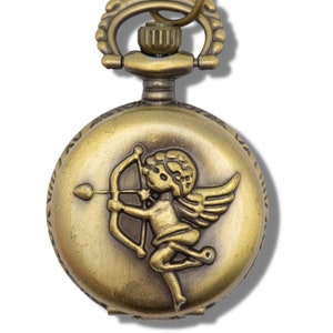 Puede incluir: Un reloj de bolsillo dorado con una cadena adjunta. La esfera del reloj presenta un grabado detallado de un querub&iacute;n sosteniendo un arco y una flecha.
