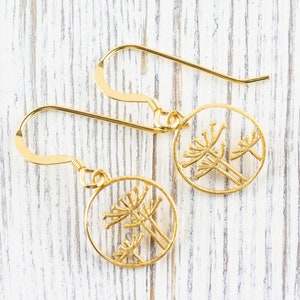 May include: A pair of gold dangle earrings with a delicate design of three stylized flowers in a circle.