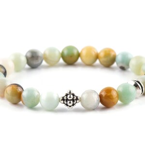 Black Gold Amazonite Genuine Gemstone Stretch Bracelet on white background. Amazonite beads are multicolor earth-tones. Center bead is a silver Bali style bead.