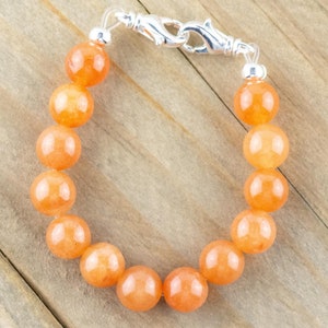 Op de afbeelding: Een armband gemaakt van oranje edelsteen kralen met een zilveren sluiting.