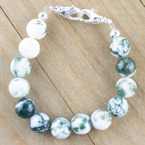 May include: A green and white agate stone bracelet with a silver clasp. The bracelet is made of round beads and is approximately 18 cm in length.