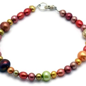 Pu&ograve; includere: Un braccialetto di perle multicolori con una chiusura argentata. Le perle sono in tonalit&agrave; di rosa, rosso, arancio, giallo e verde.